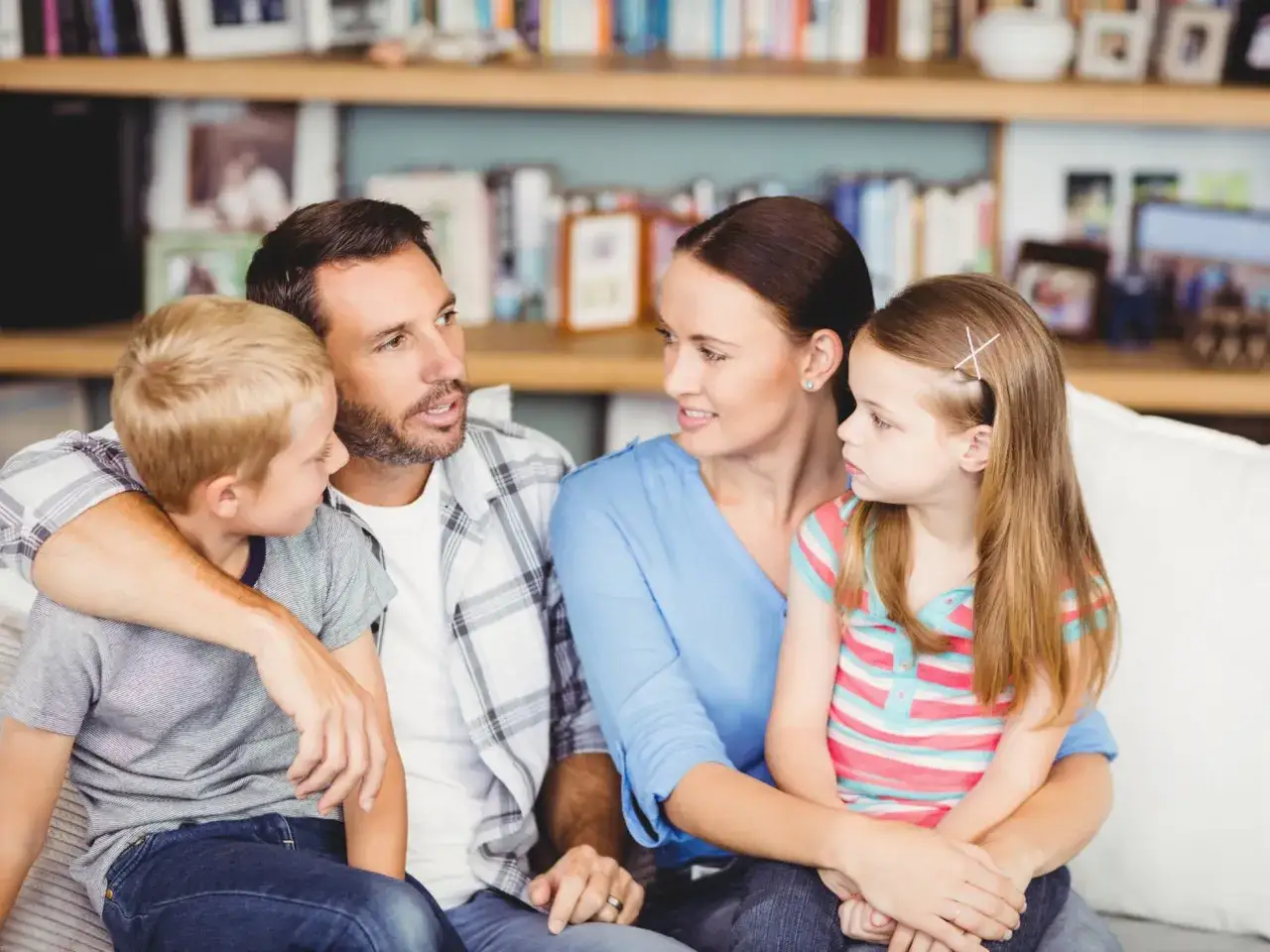 Familia conversando en el sofá, fomentando la autoestima en niños de 9 a 12 años.
