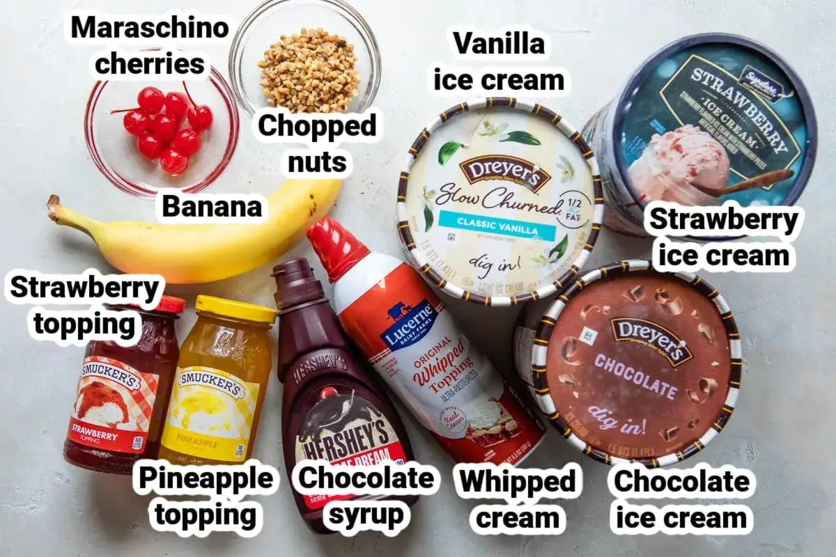 Ingredienser f&ouml;r en klassisk banana split: banan, vanilj-, jordgubbs- och chokladglass, jordgubbs- och ananass&aring;s, chokladsirap, vispgr&auml;dde, hackade n&ouml;tter och k&ouml;rsb&auml;r.