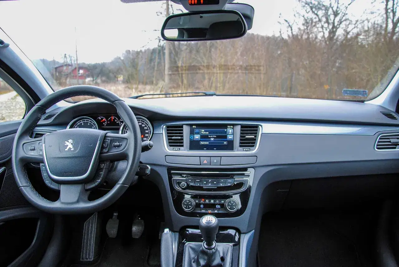 Wnętrze Peugeota 508: kierownica, deska rozdzielcza z ekranem multimediów i nawigacją. Wiele osób szuka peugeot 508 opinie przed zakupem.