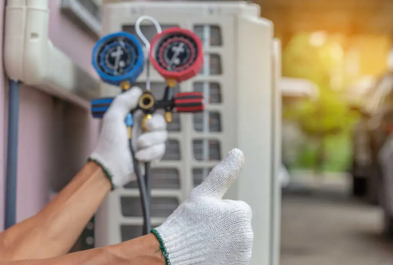 Tecnico con guanti controlla il condizionatore, manometro per scarico di gas. Pollice in su per lavoro ben fatto.