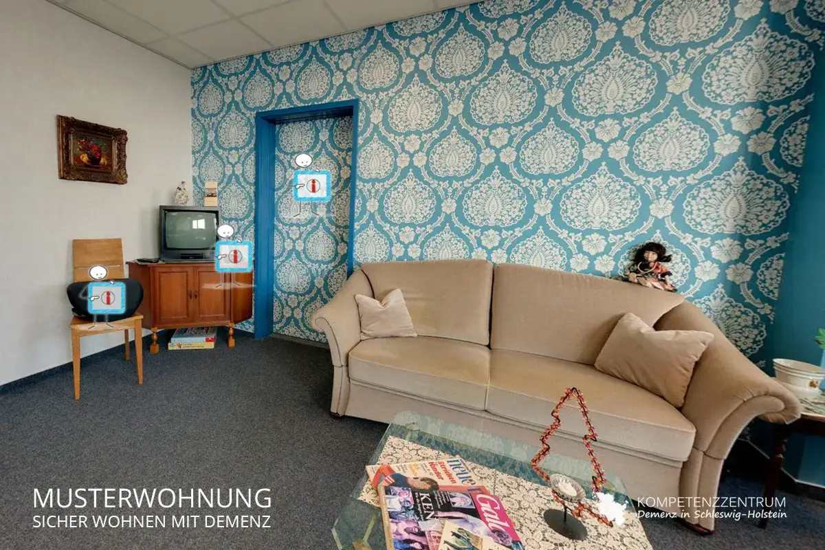 Gem&uuml;tliches Wohnzimmer mit Couch, Fernseher und Bildern. Ein Ort, der Sicherheit f&uuml;r Menschen mit Alzheimer Demenz bietet.