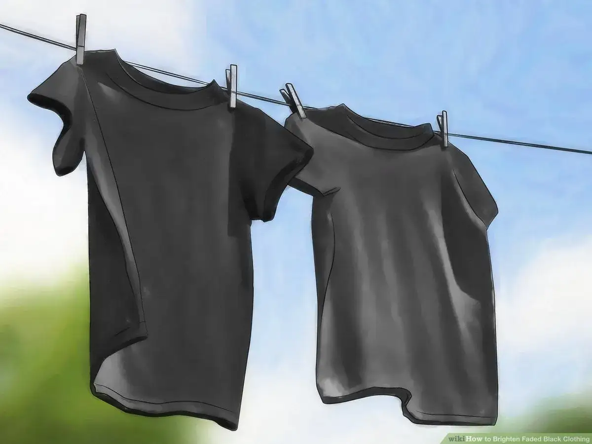 Dwa czarne t-shirty wiszą na sznurku, susząc się na tle błękitnego nieba. Dowiedz się, jak przywrócić czarny kolor ubraniom.