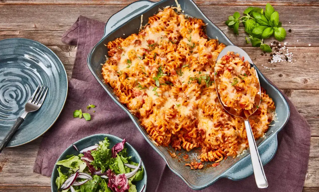 Herzhafter Nudelauflauf mit Hackfleisch, &uuml;berbacken mit K&auml;se, serviert mit frischem Salat.