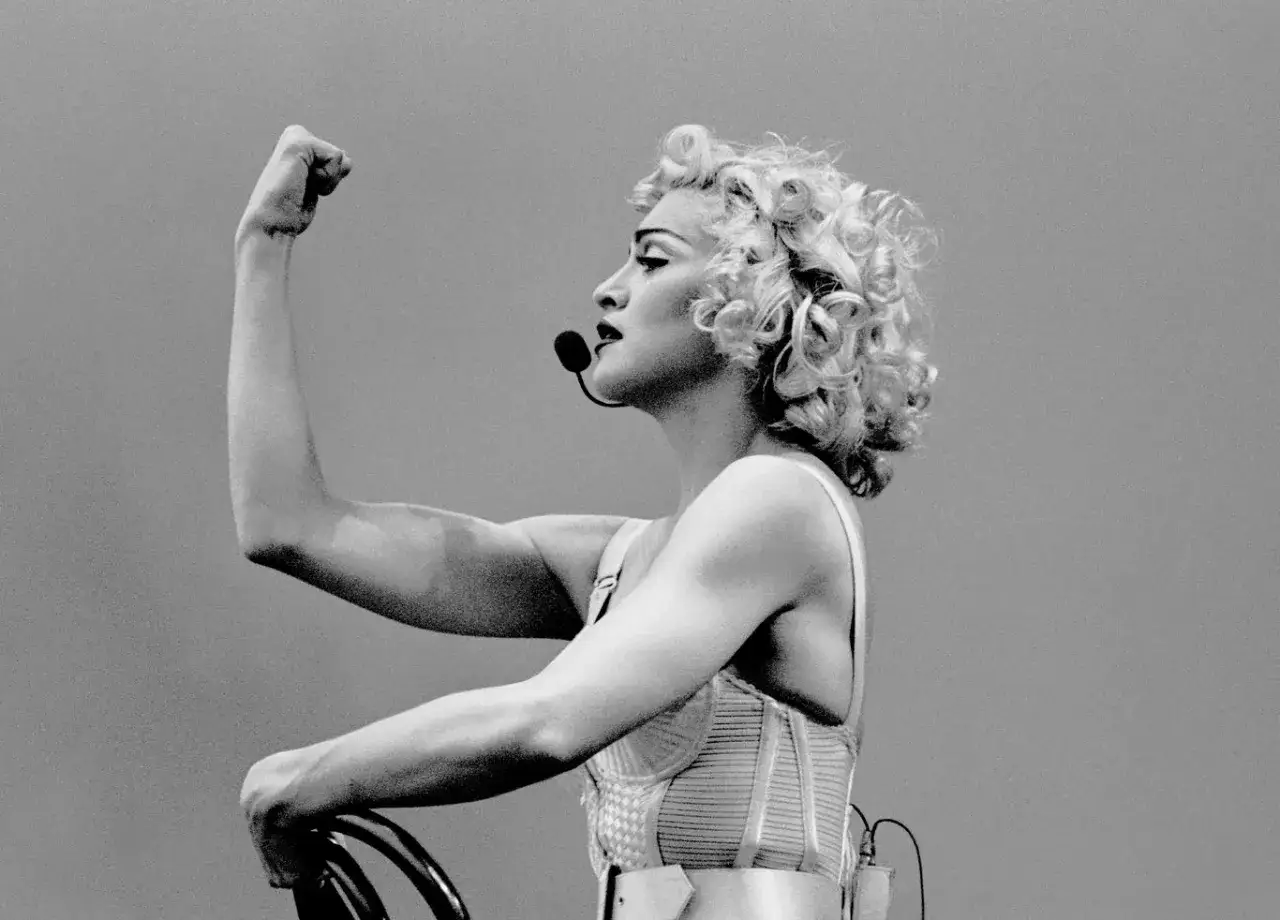 Ikona popu z burzą blond loków i mikrofonem, prezentująca siłę. To właśnie znaczy vogue – styl, pewność siebie i wyrazistość.