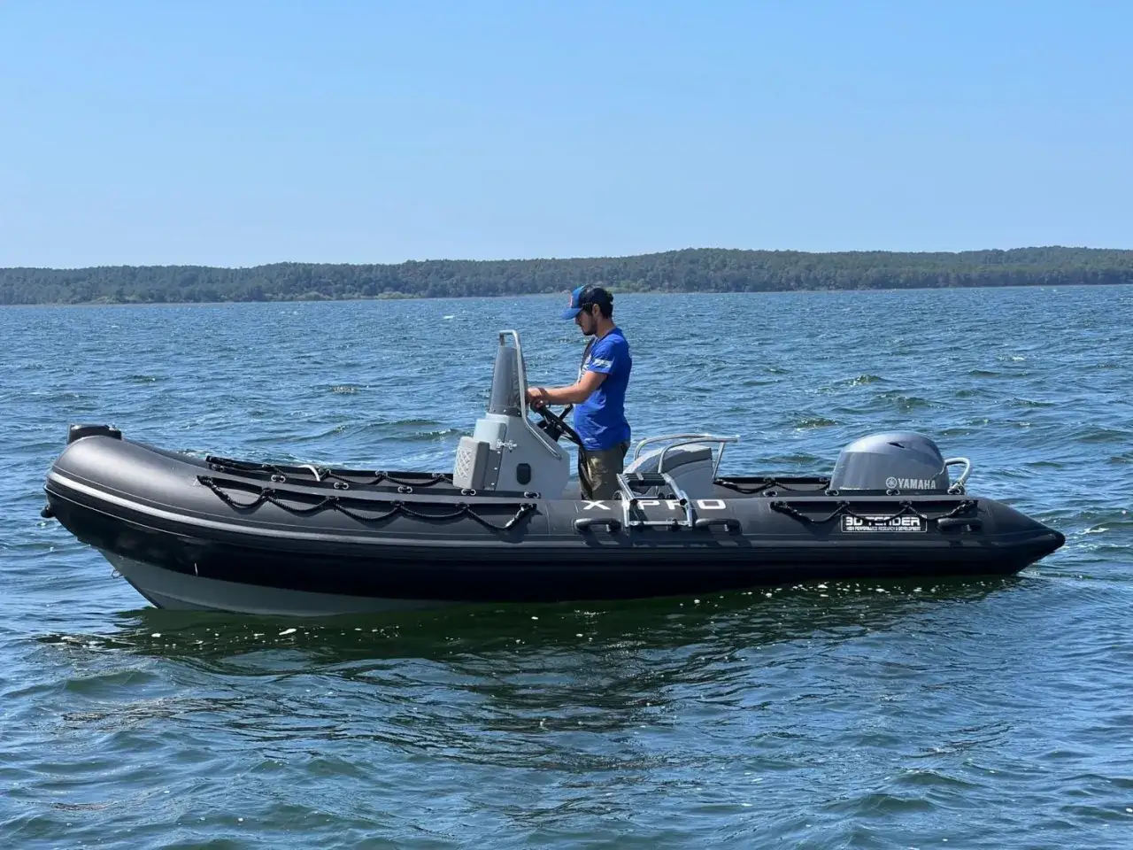 Bateau semi-rigide noir sur l'eau, avec un homme au volant. Le matériau hypalon assure une grande durée de vie.