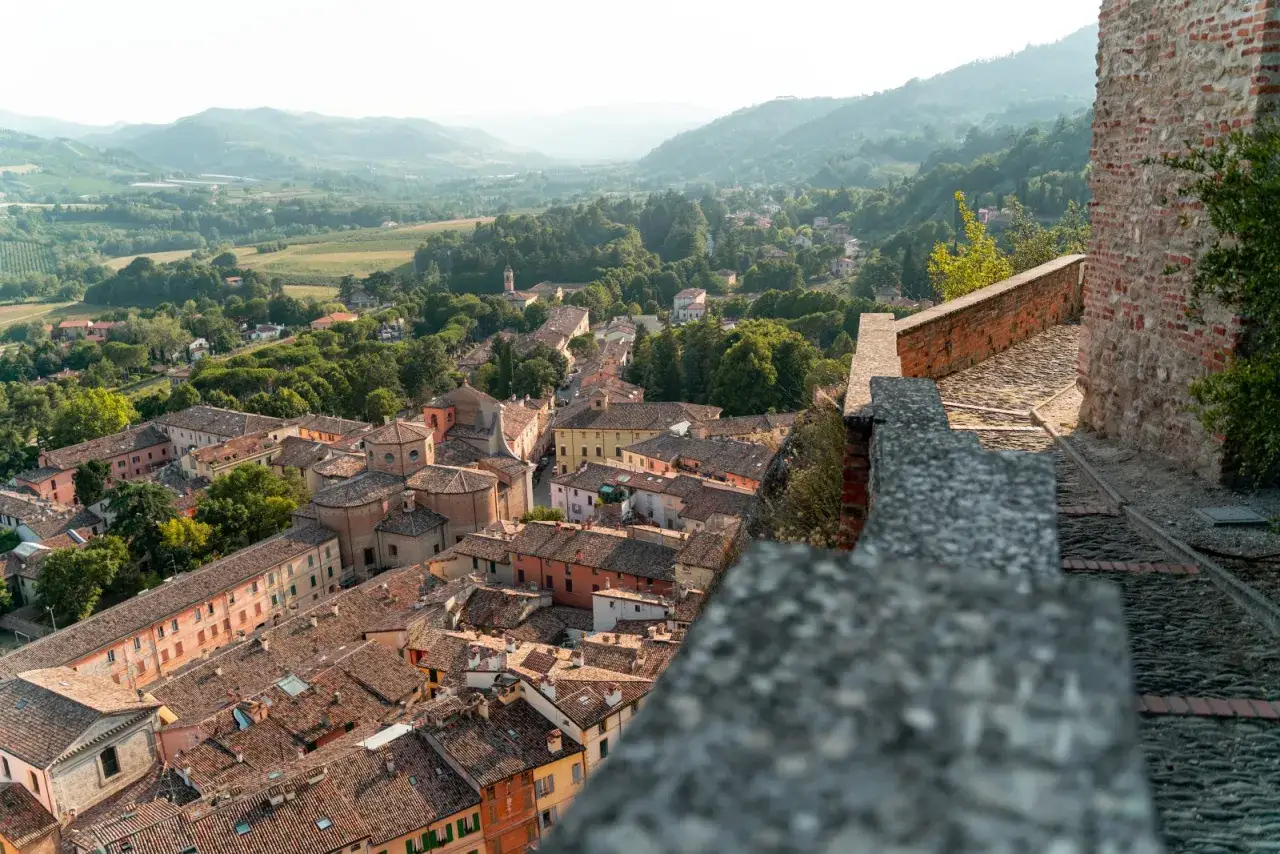 Panoramica di un borgo da visitare in Romagna, con tetti in cotto, colline verdi e un sentiero in pietra.