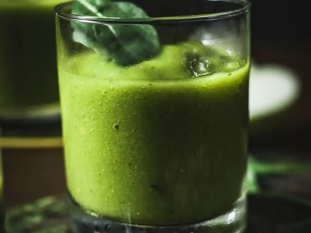 Orzeźwiający zielony drink z bazylią, ozdobiony świeżym listkiem, idealny na upalne dni.