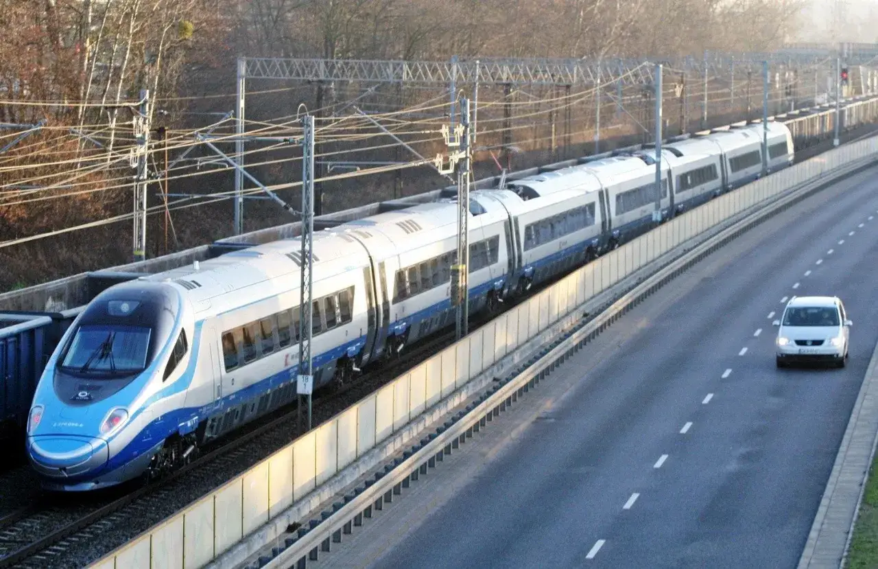 Pendolino z Katowic do Gdańska pędzi po torach, obok autostrady.