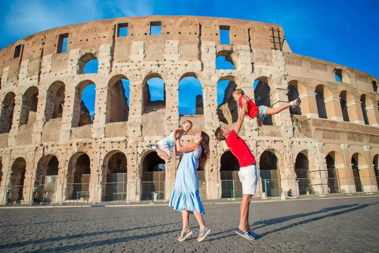 Familia jugando con ni&ntilde;os frente al Coliseo en Roma. Los padres levantan a sus hijos en el aire, creando recuerdos inolvidables.