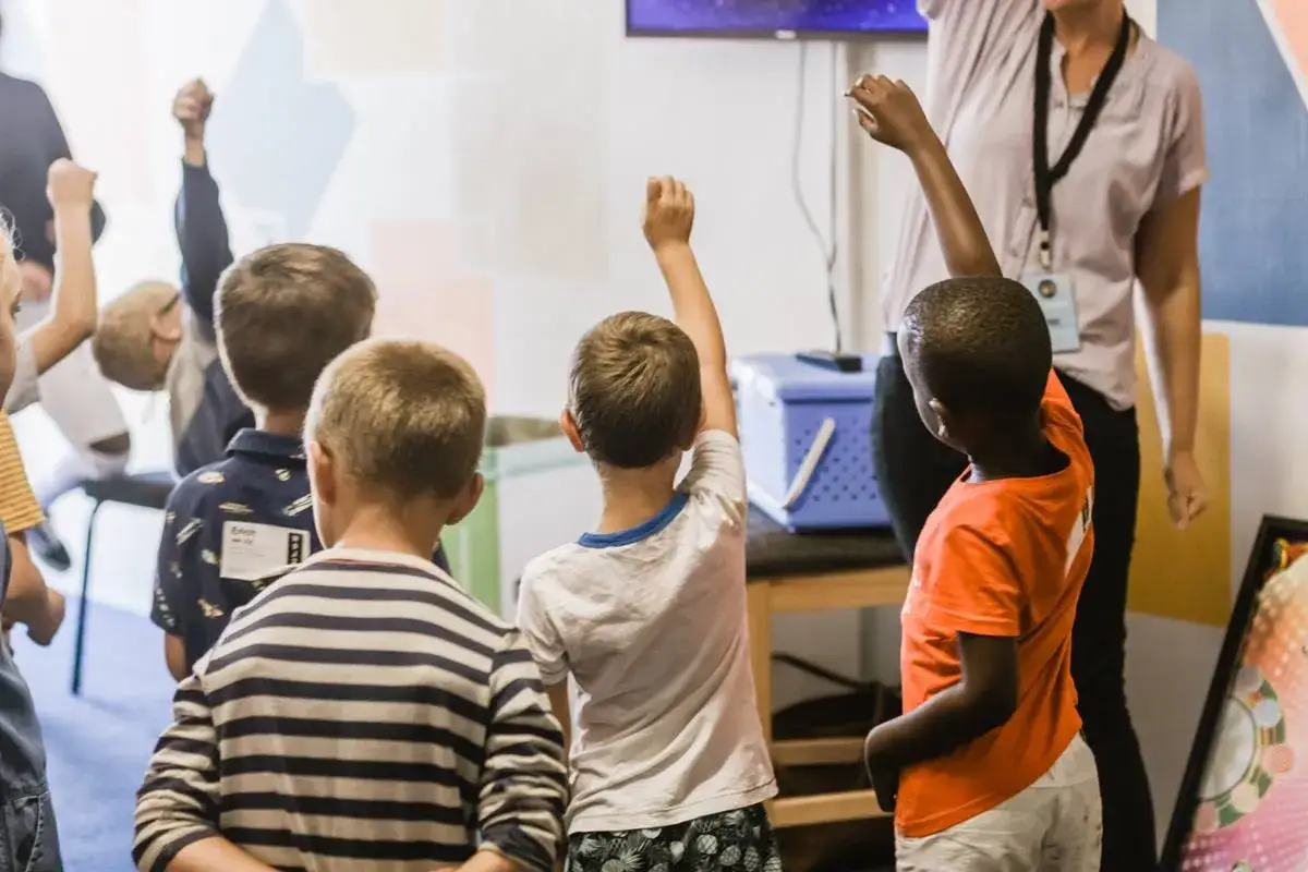 Bambini con le braccia alzate, impegnati in attivit&agrave; che stimolano le funzioni esecutive. Esercizi ludici per allenare mente e corpo.