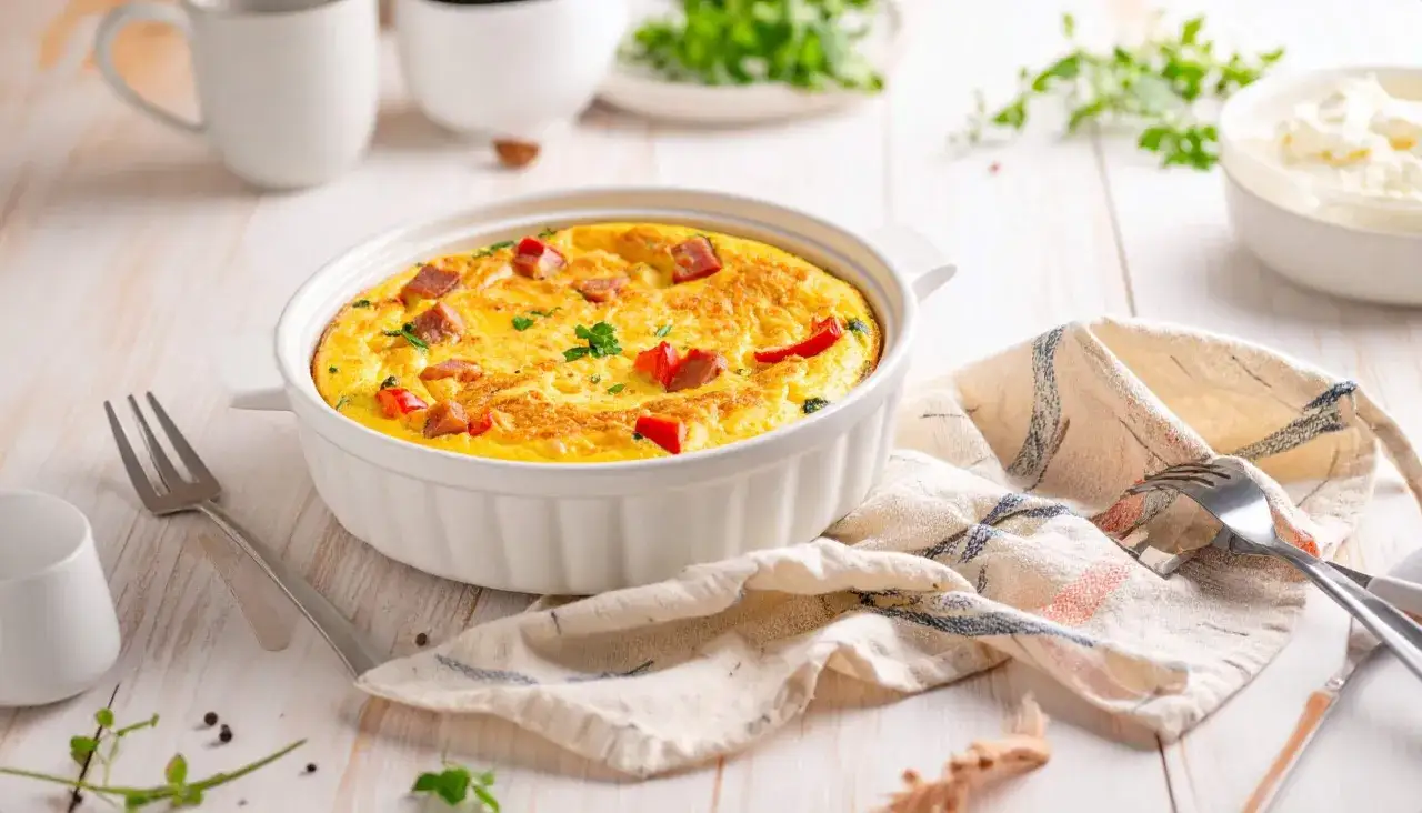 Pyszny omlet z airfryer, z kawałkami kiełbasy i papryki, udekorowany natką pietruszki, gotowy do podania.