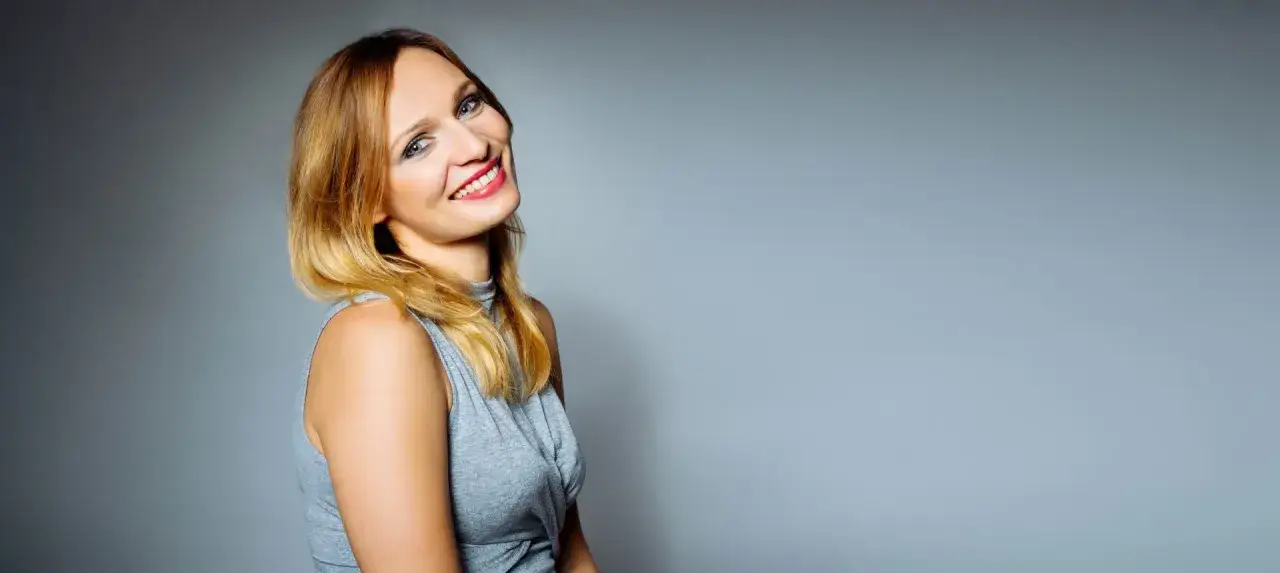 Uśmiechnięta modelka z rudymi włosami, gotowa do podpisania umowy wzór.