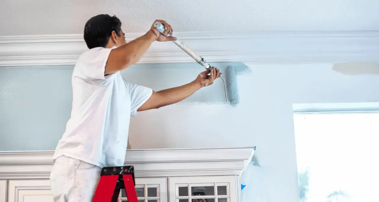 Pittore imbianca il soffitto con un rullo. La temperatura ideale per imbiancare &egrave; tra i 10&deg;C e i 25&deg;C.