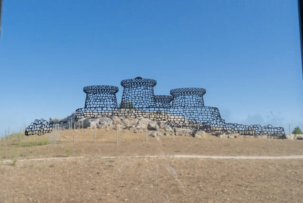 Disegno stilizzato del nuraghe Genna Maria, con le sue torri che si stagliano contro il cielo azzurro.