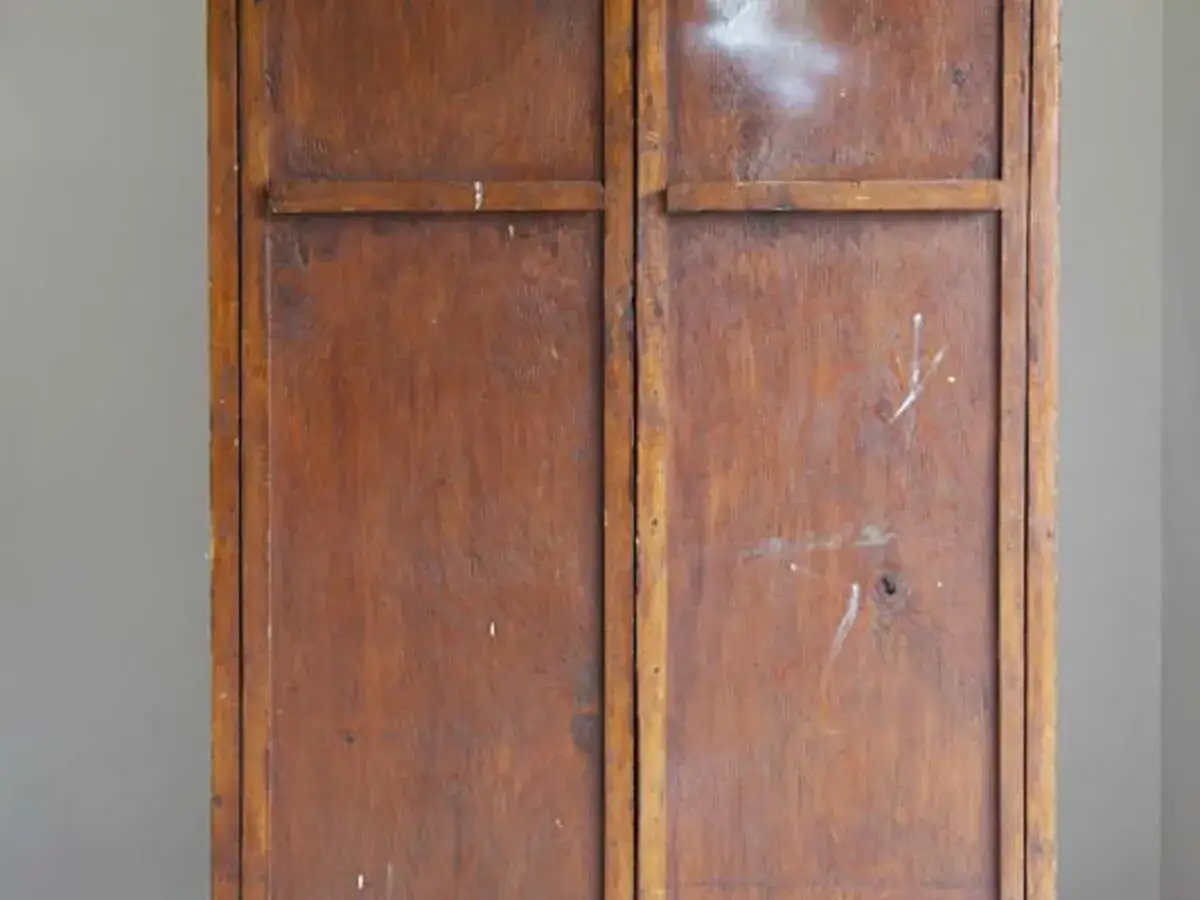 Portes d'une armoire ancienne en bois vernis, prêtes à être relookées. Le bois est marqué par le temps.