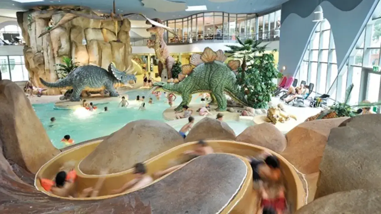 Kinder rutschen im tropischen Badeparadies mit Dinosauriern. Perfekt für die Herbstferien in Hamburg!