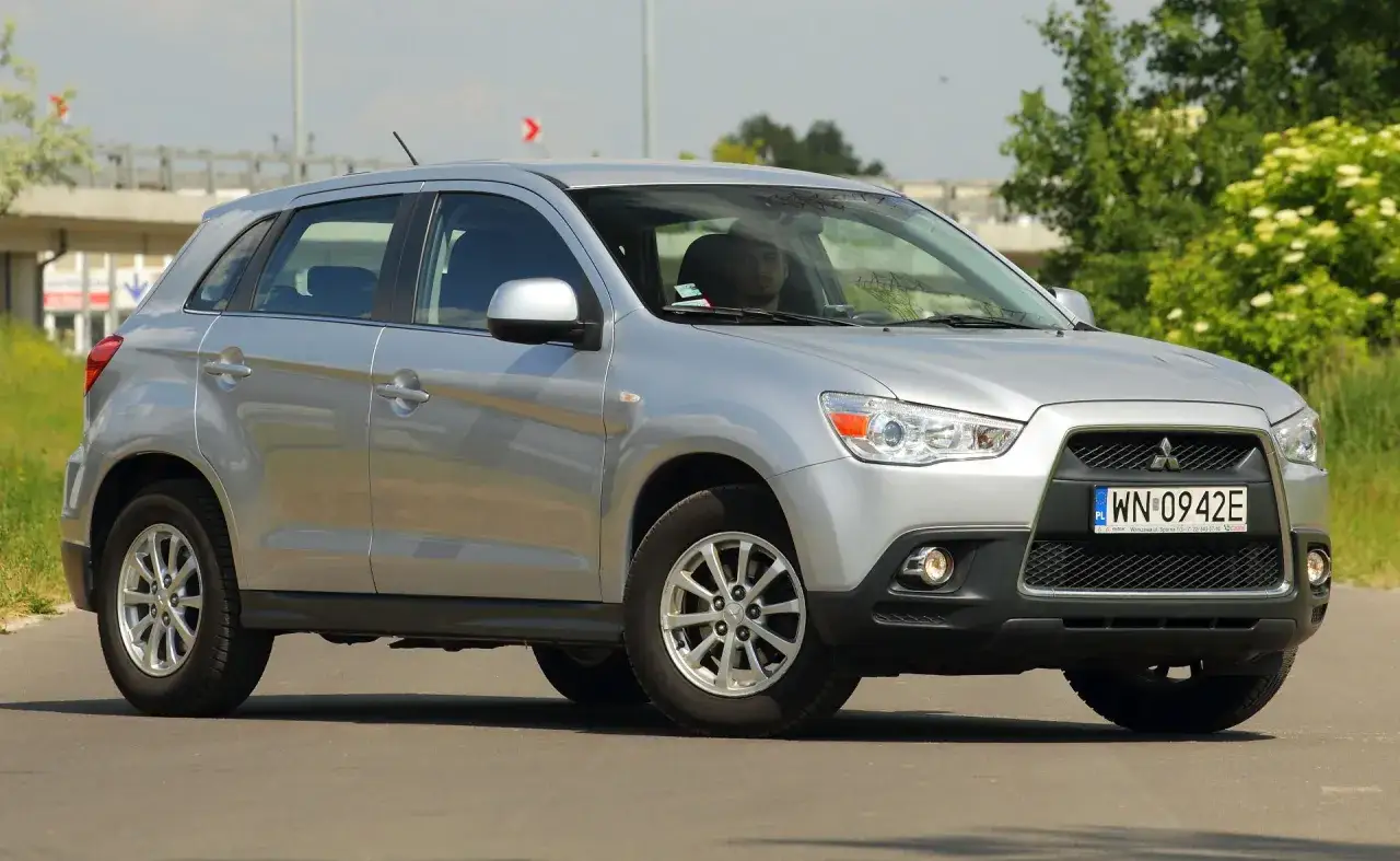 Srebrny Mitsubishi ASX 1.6 benzyna na drodze, z kierowcą za kierownicą.