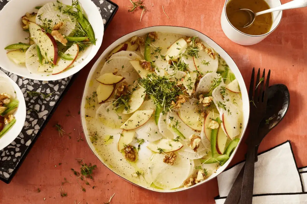 Frischer Rettichsalat mit Apfel, garniert mit Walnüssen und Kresse. Ein leichter und knackiger Genuss.