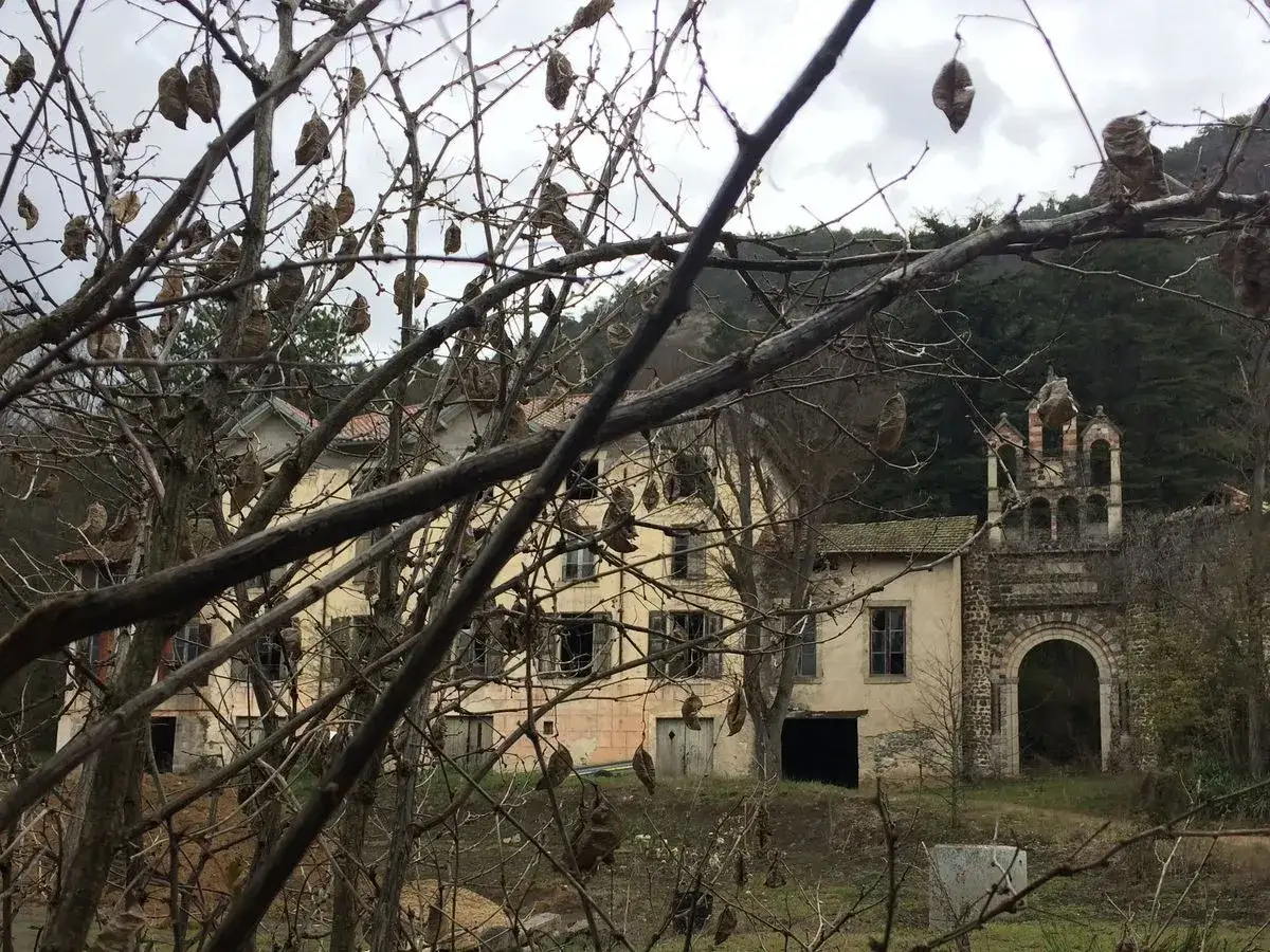 Maison abandonn&eacute;e et arche orn&eacute;e, un site d'urbex &agrave; Clermont-Ferrand, entour&eacute; d'arbres d&eacute;nud&eacute;s.