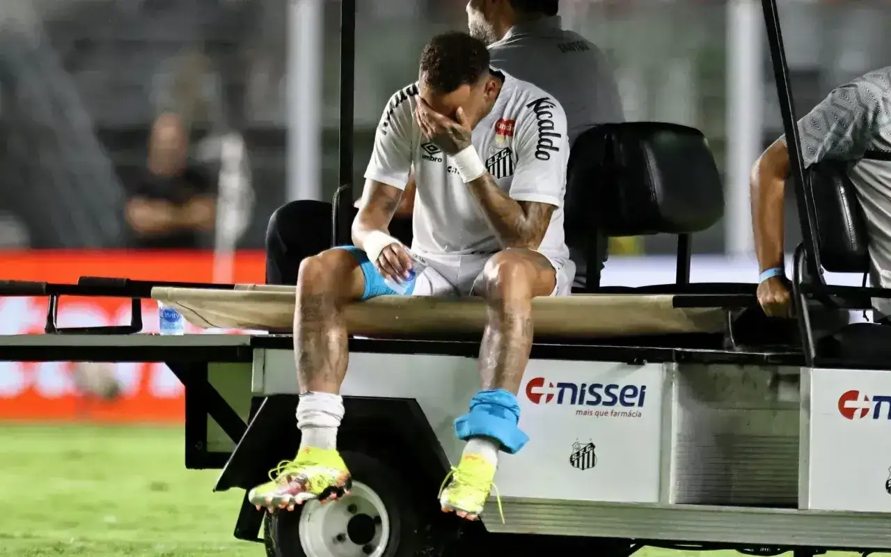 Neymar siedzi na wózku golfowym, trzymając się za twarz. Wygląda na to, że doznał kontuzji.