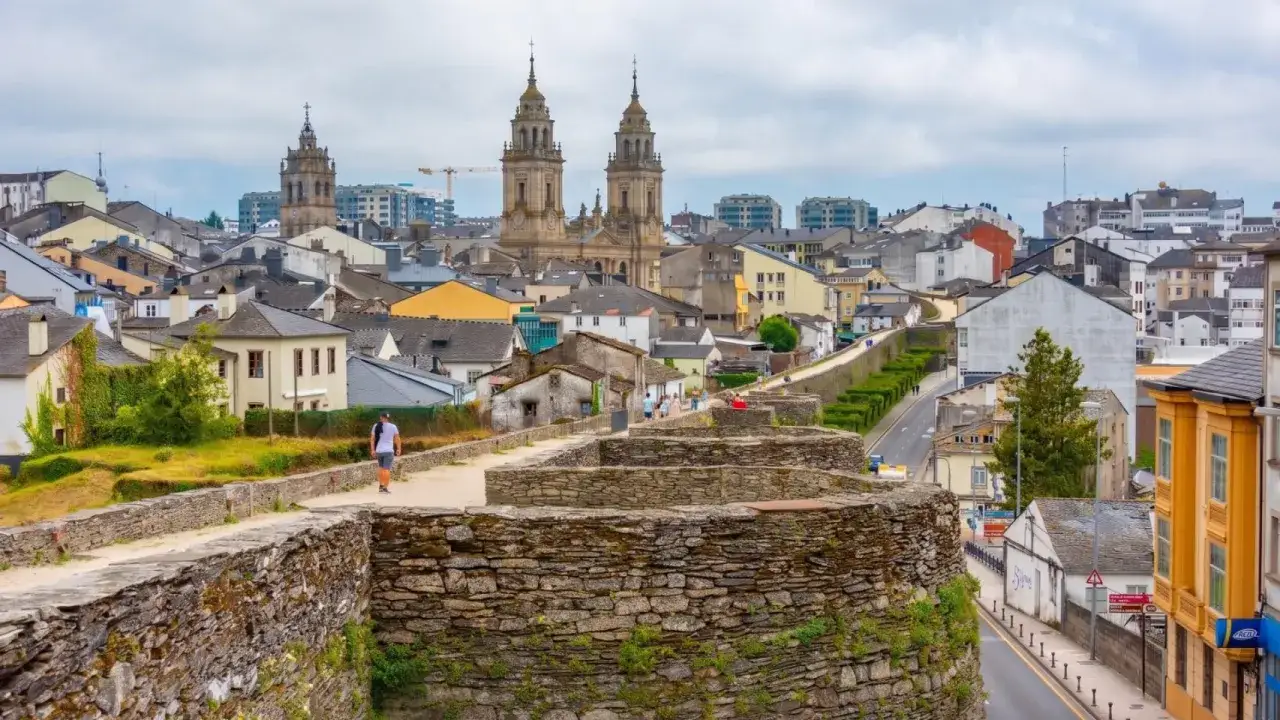 Un paseo por la fortaleza de Lugo, con sus murallas de piedra y la ciudad extendiéndose tras ellas, coronada por la imponente catedral.
