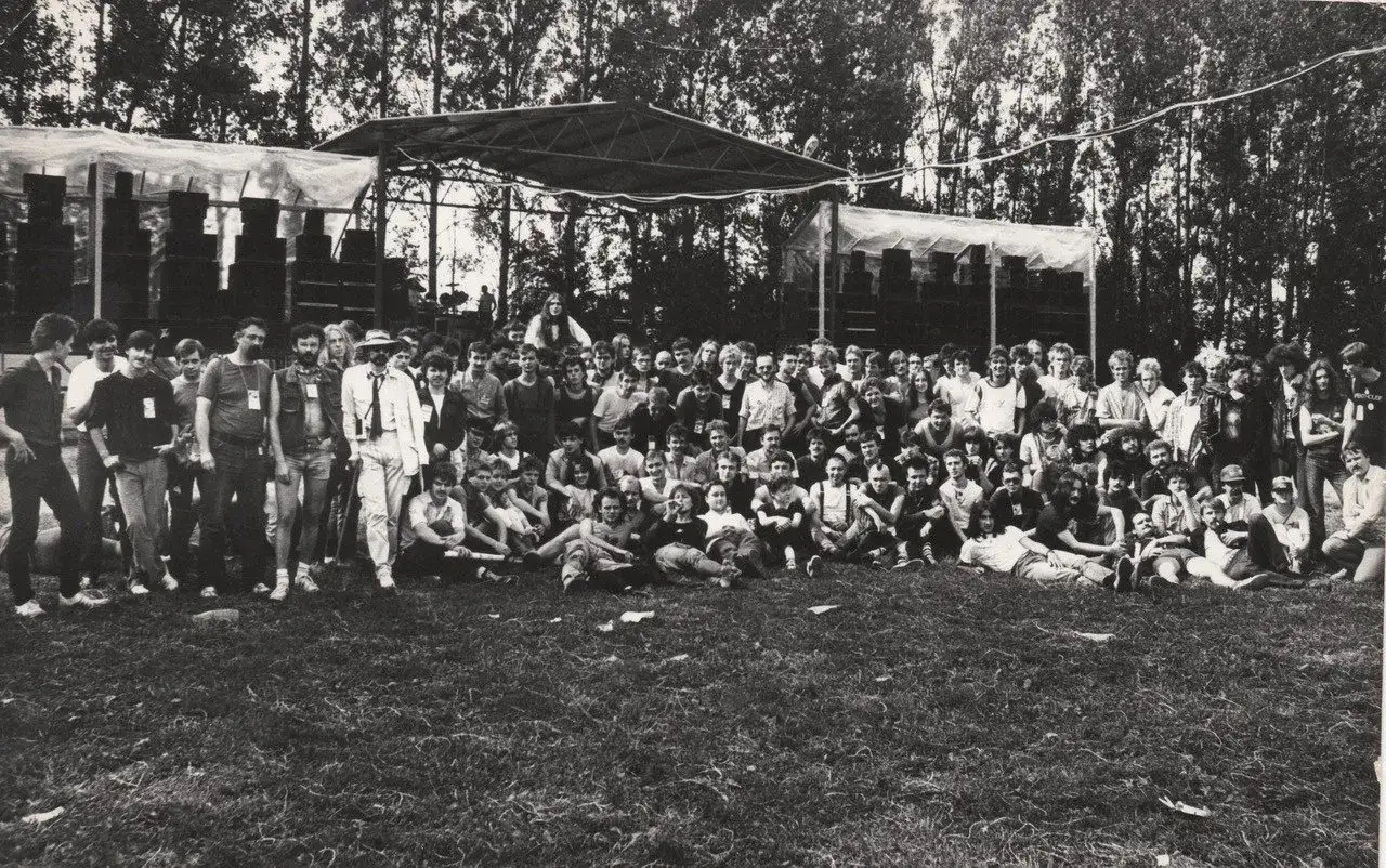 Grupa ludzi pozuje do zdjęcia na tle sceny podczas festiwalu w Jarocinie.
