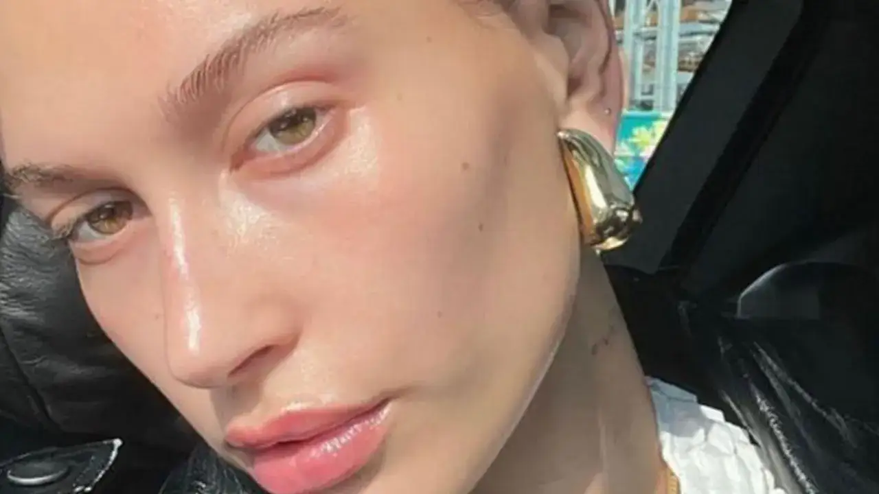 Rostro con piel luminosa y labios brillantes, luciendo un pendiente dorado. La clave para esta piel radiante podr&iacute;a ser la cosm&eacute;tica con p&eacute;ptidos.