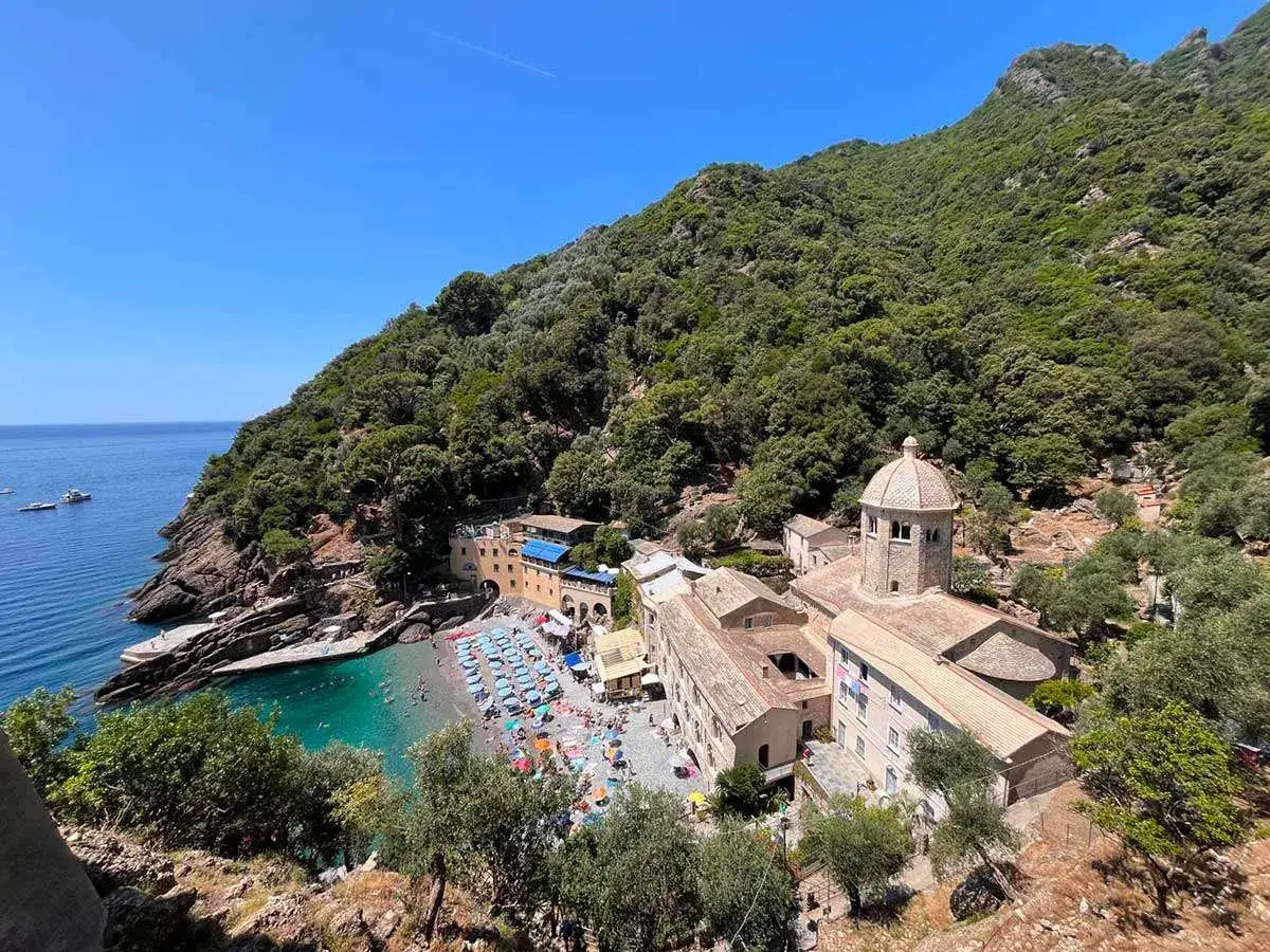Baia con spiaggia e monastero, ideale per chi cerca dove dormire sul Cammino del Tigullio. Mare azzurro e vegetazione rigogliosa.