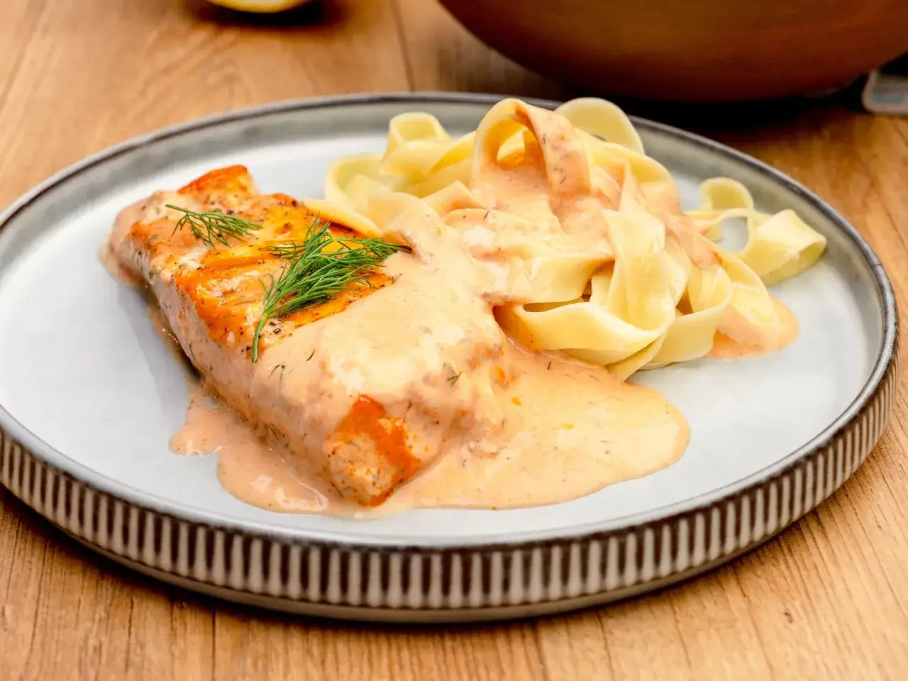 Ein saftiges Lachsfilet mit cremiger Sauce und Bandnudeln. Ein k&ouml;stlicher Lachs Sahne Gratin, garniert mit Dill.