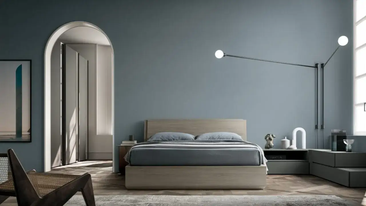 Camera da letto moderna con letto in legno, pareti blu polvere e un'elegante lampada a sospensione. Idee pareti camera da letto moderna.