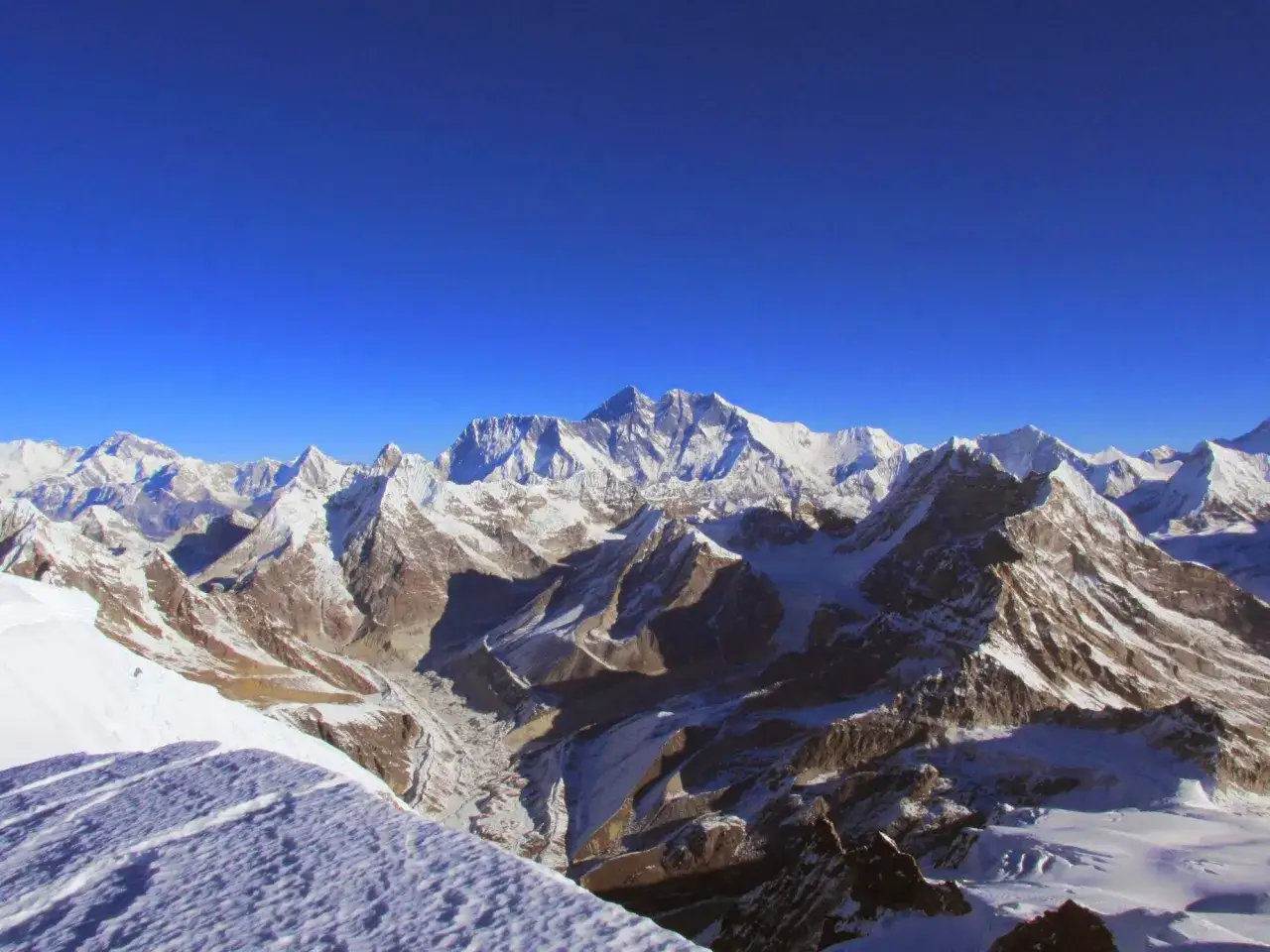 Widok na ośnieżone szczyty Himalajów, z majestatycznym Mera Peak w oddali, pod błękitnym niebem.
