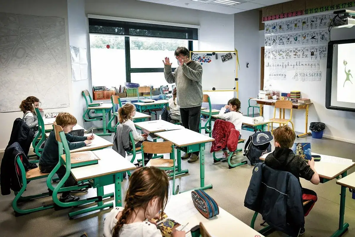 Nauczyciel prowadzi lekcję we francuskiej szkole. Dzieci siedzą w ławkach, ucząc się. Ciekawostki o edukacji we Francji mogą obejmować tradycyjne metody nauczania.