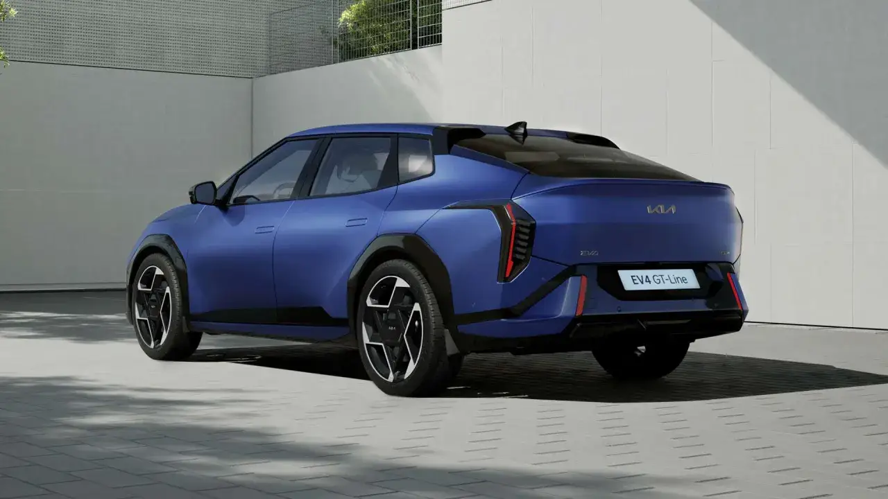 Niebieski Kia EV4 GT-Line z futurystycznym tyłem i pionowymi światłami, zaparkowany na betonowym podjeździe.
