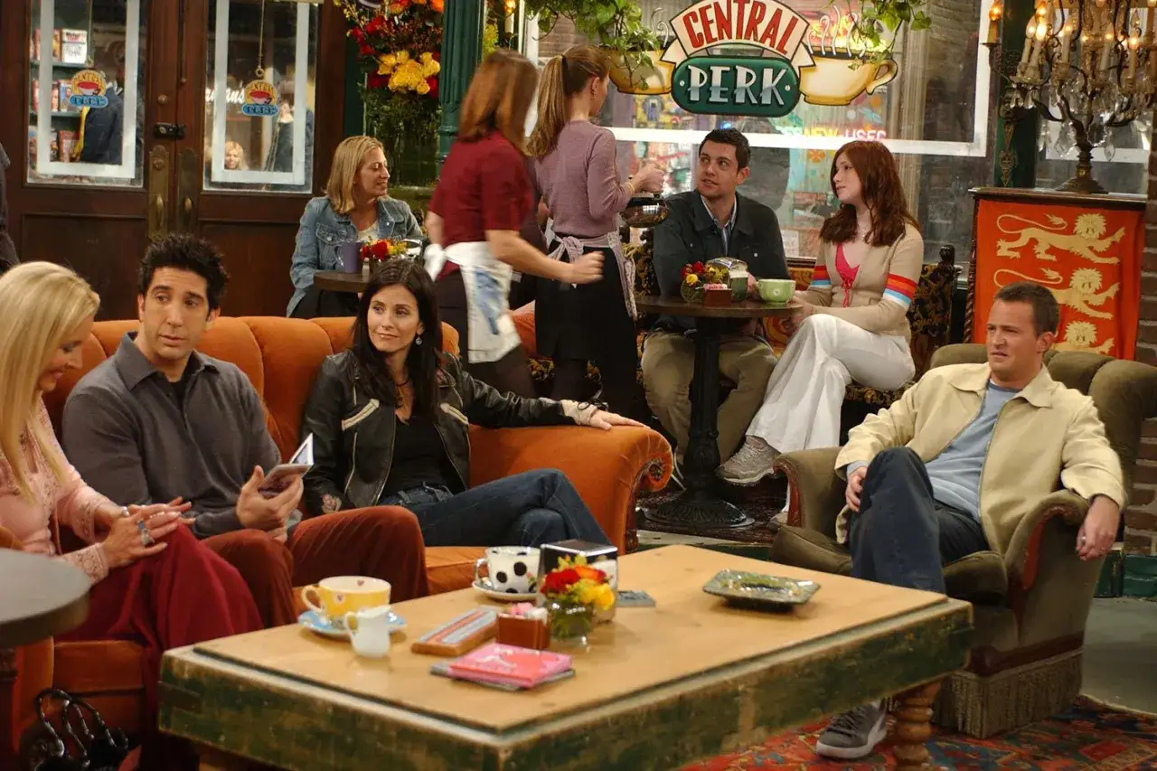 Przyjaciele z Central Perk, od przyjaźni do miłości. Ross, Rachel, Monica, Chandler, Phoebe i Joey siedzą na kanapie i fotelach.