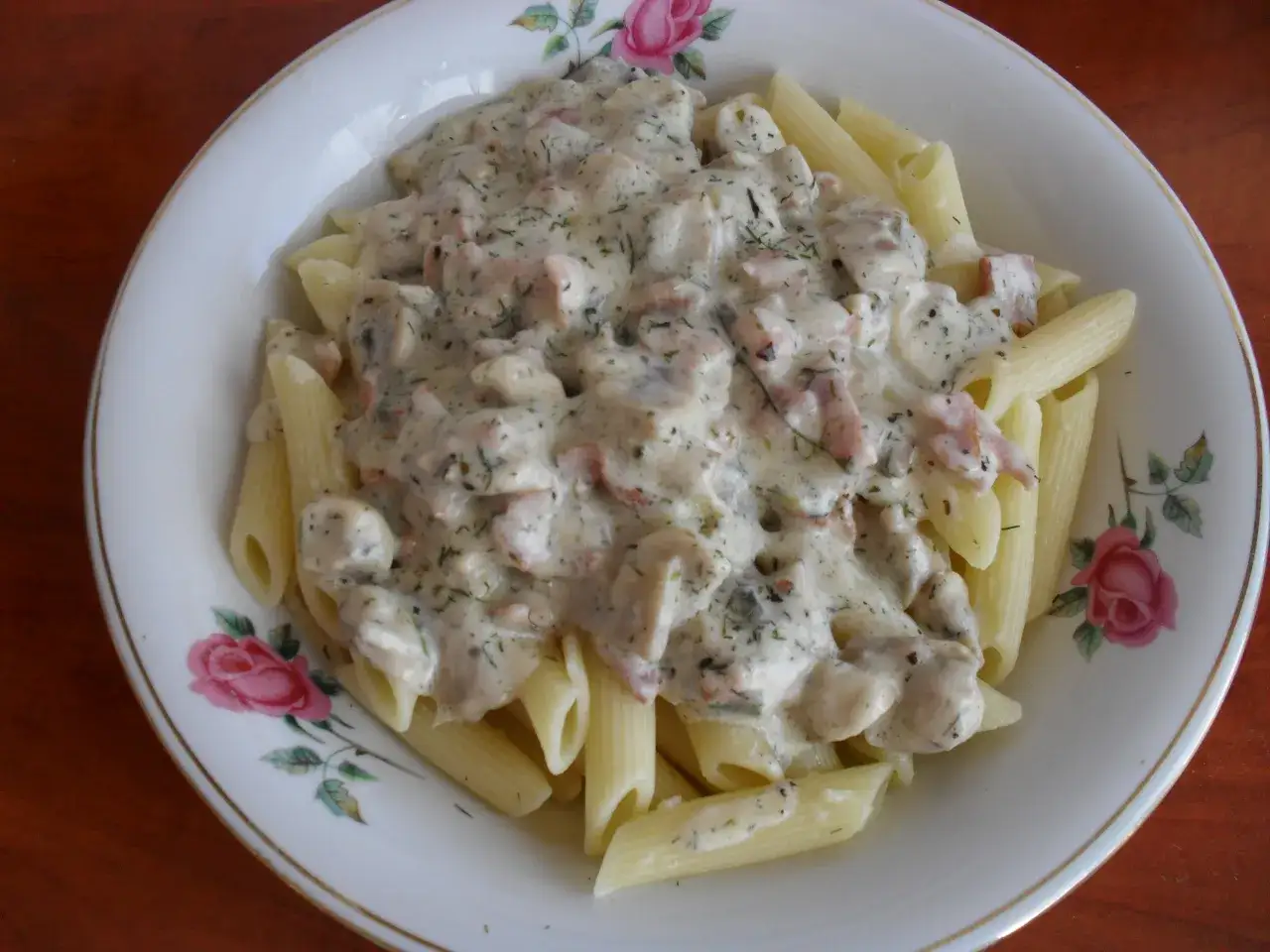 Penne w kremowym sosie pieczarkowym z kawałkami boczku i koperkiem. Pyszne danie, które zachwyci każdego.