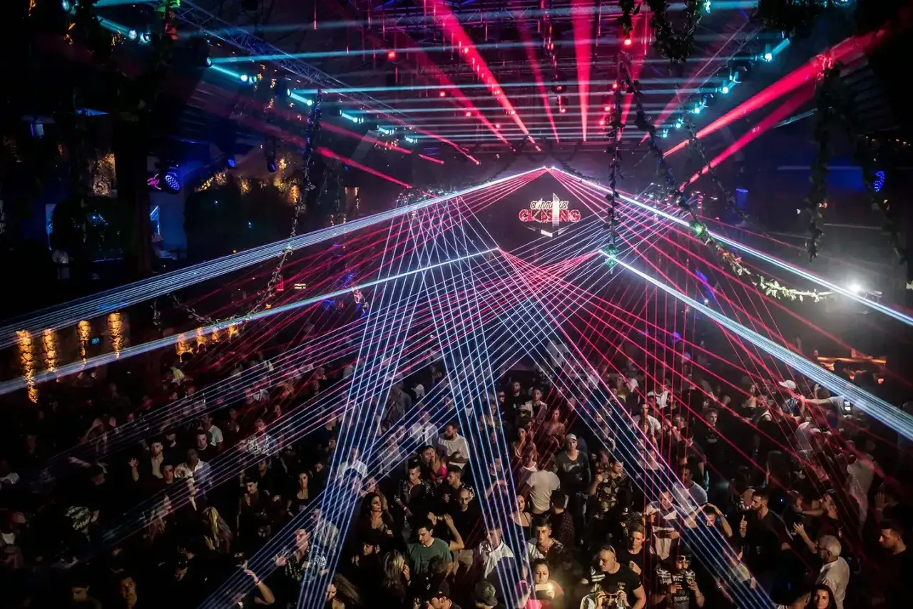 La folla balla sotto un tripudio di laser rossi e blu all'Amnesia Ibiza, un'esperienza indimenticabile.