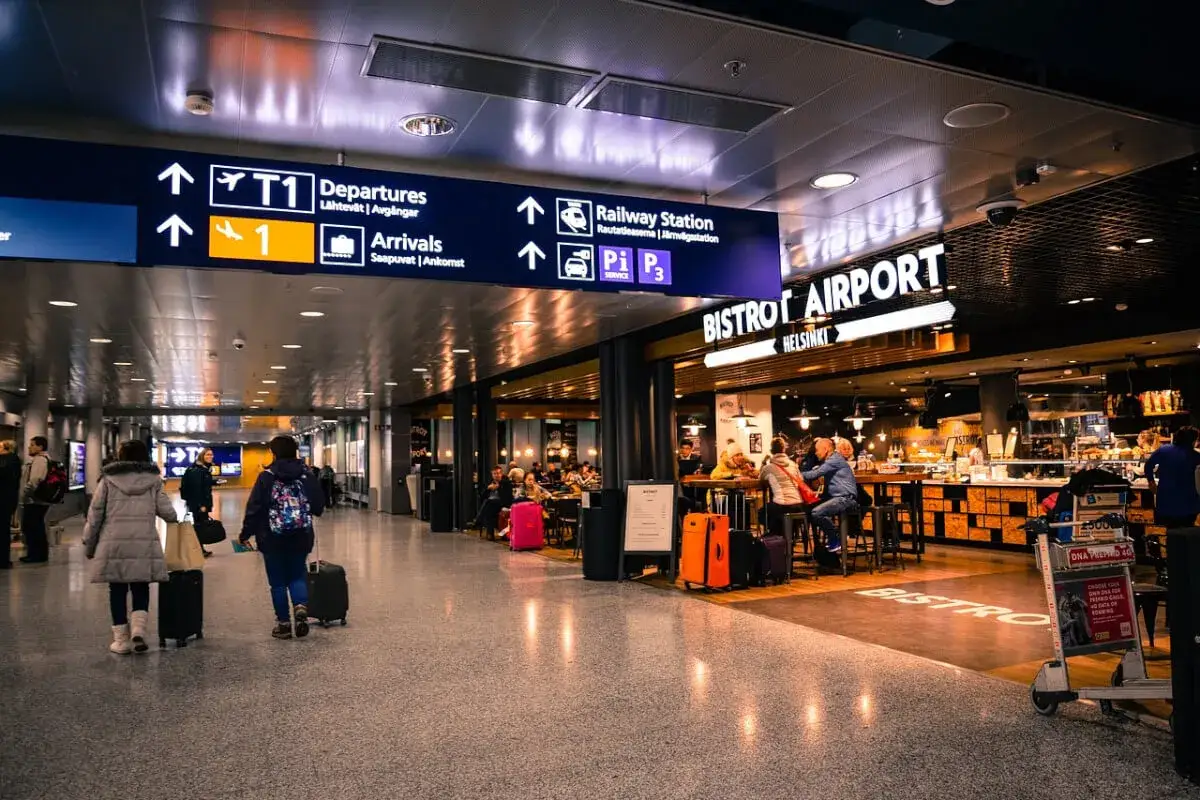 W Bistro Airport Helsinki ludzie siedzą przy stolikach, pijąc i jedząc. To miejsce sugeruje, że czy na lotnisku można pić alkohol.