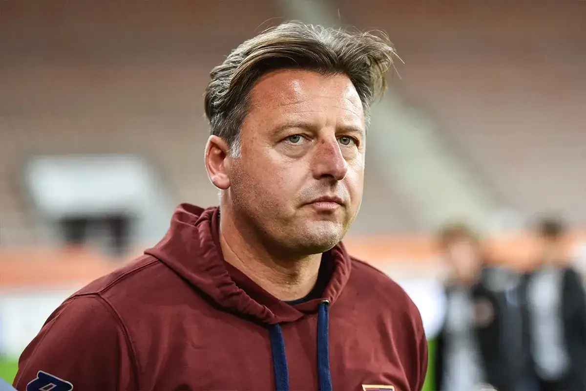 Trener w bordowej bluzie z kapturem, skupiony na boisku. Składy: Atalanta – Udinese.