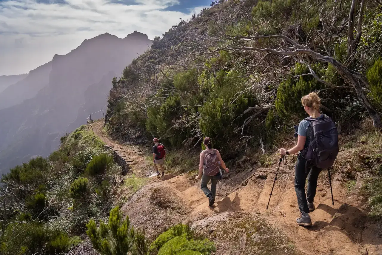 Wanderer auf einem schmalen Pfad in Madeira, die Berge im Nebel. Perfekte Packliste Madeira für diese Wanderung.