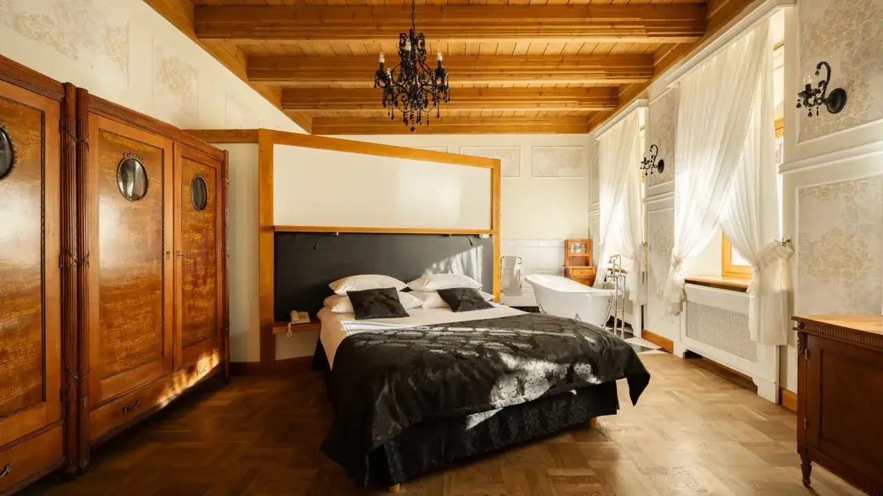 Elegancki pokój w hotelu Belvedere Resort & Spa z łóżkiem, wanną i zabytkową szafą.