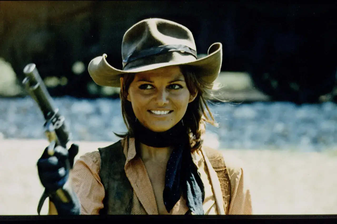 Claudia Cardinale w westernowym kapeluszu i z rewolwerem, gotowa do akcji w jednym z niezapomnianych filmów.