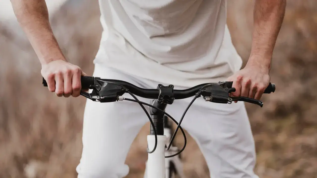 Rowerzysta trzyma kierownicę, która może być dobrym wyborem, jeśli zastanawiasz się, jaka kierownica do roweru trekkingowego będzie najlepsza.