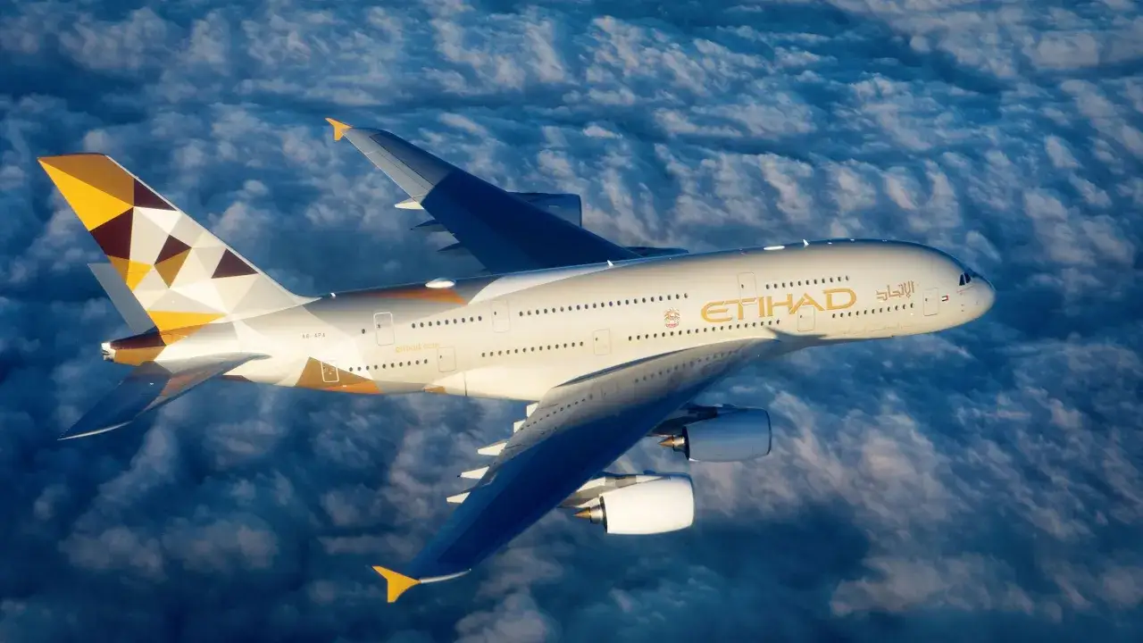 Airbus A380 800 Etihad z charakterystycznym malowaniem leci nad chmurami.