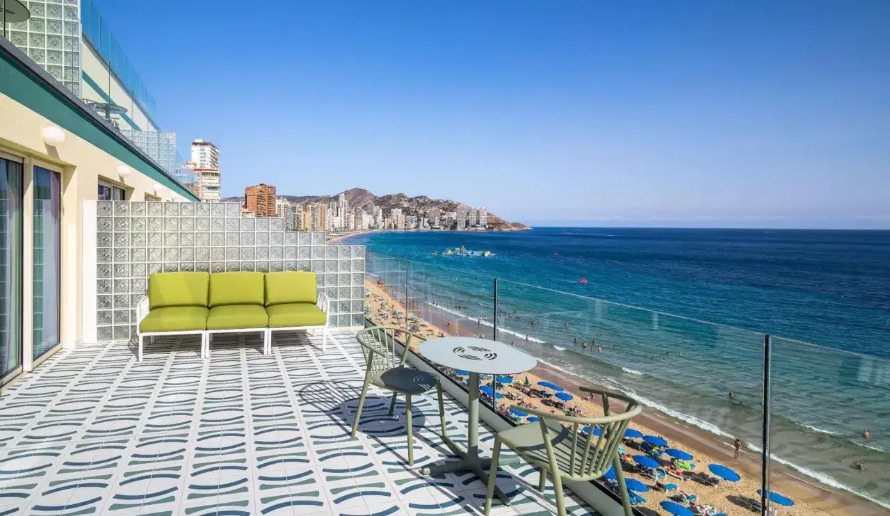 Terraza con sofá verde y mesa, vistas a la playa y al mar de Benidorm. Barceló Benidorm.