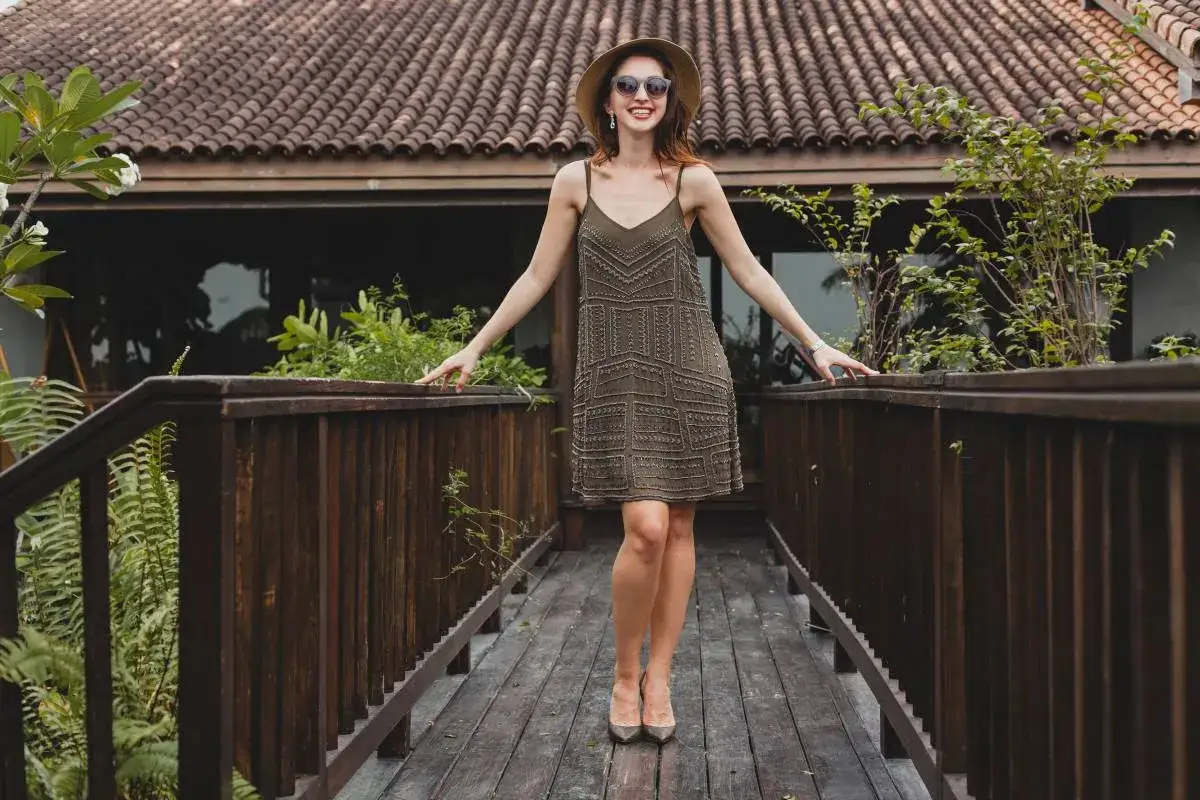 Uśmiechnięta kobieta w sukience w stylu lat 20. i kapeluszu na drewnianym molo. Stylowa figura kielich.