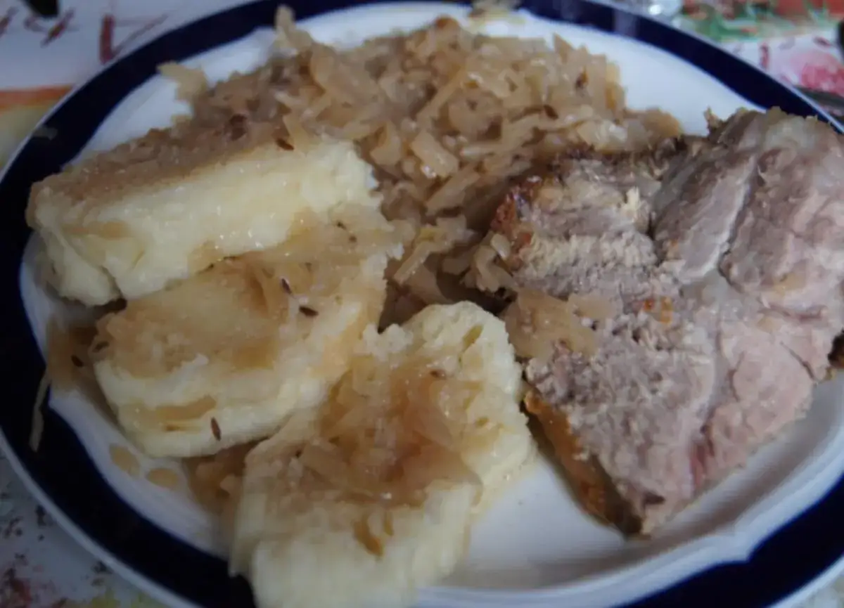 Ein Teller mit tschechischem Schweinebraten, Knödeln und Sauerkraut.