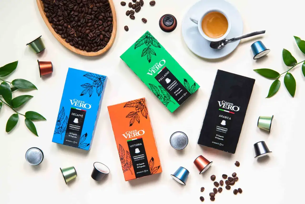 Scatole di caffè in capsule Caffe Vero, tra cui la varietà Arabica, con chicchi di caffè e una tazzina di espresso.