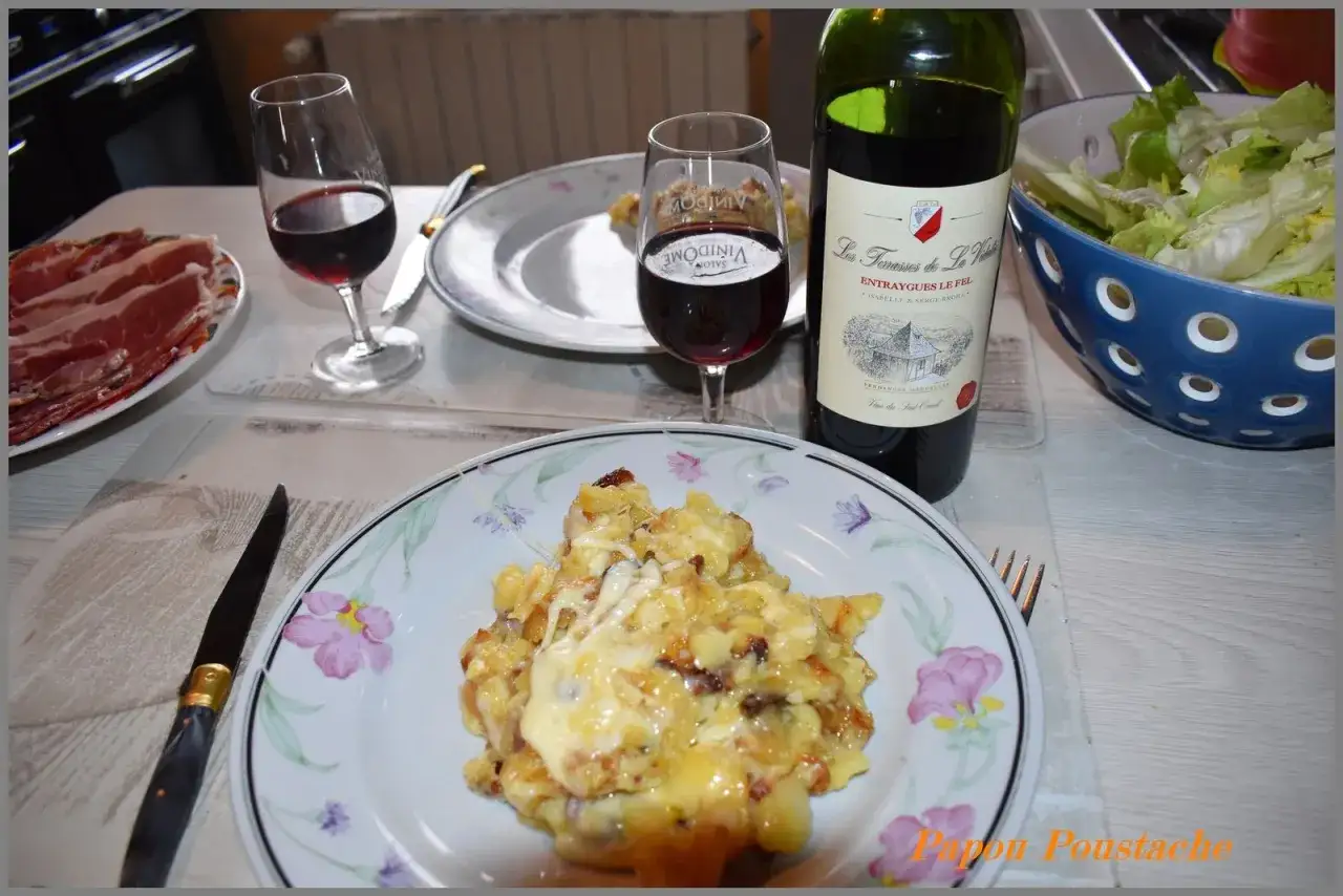 Un repas convivial avec un vin rouge et une généreuse truffade, accompagné de charcuterie et d'une salade verte.