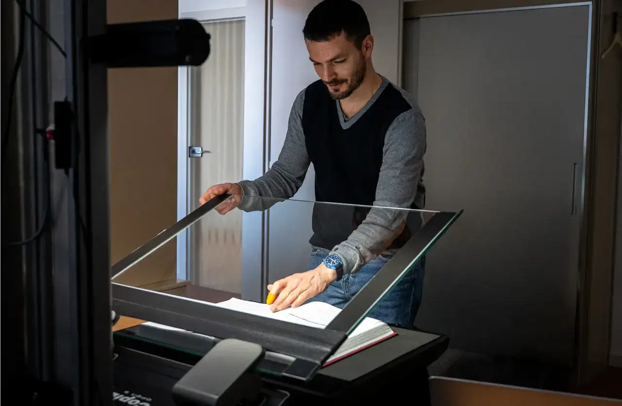 Un homme num&eacute;rise des documents pour les archives du Bas-Rhin. Il utilise un scanner sp&eacute;cial pour pr&eacute;server le patrimoine.