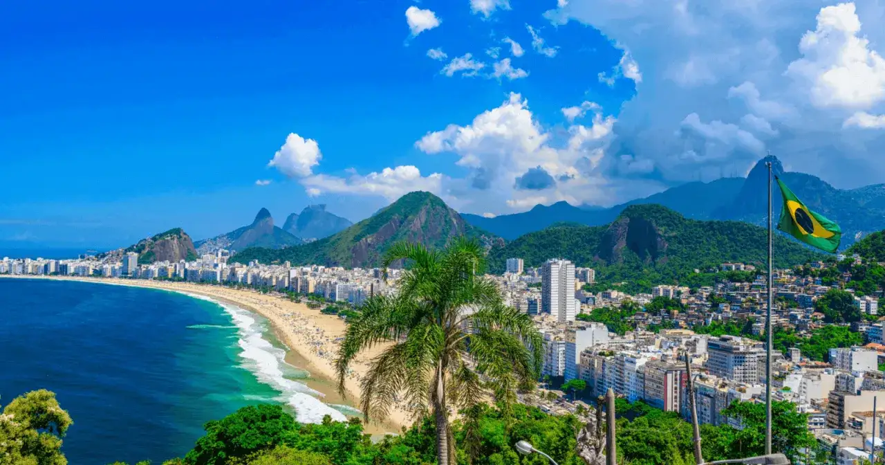 Blick auf Copacabana in Rio de Janeiro. Die brasilianische Flagge weht im Wind. Perfekt für die brasilien beste reisezeit.